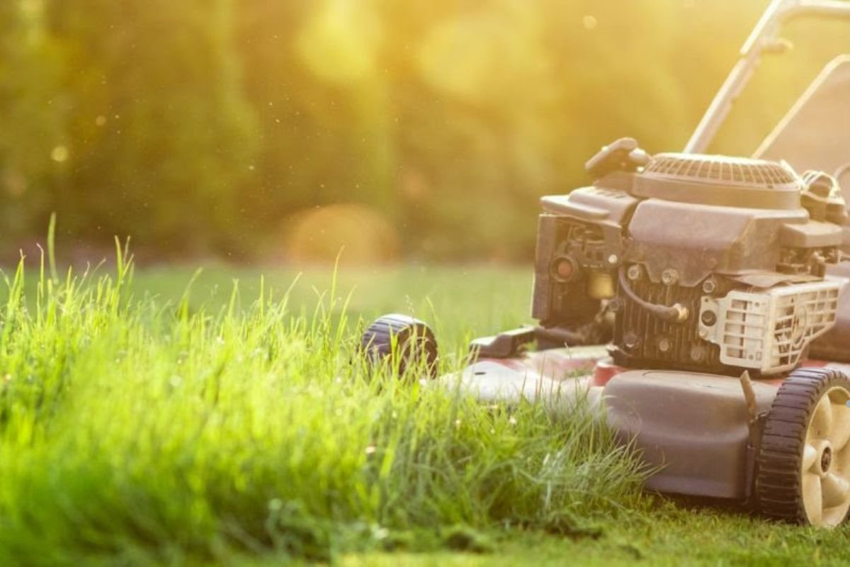A lawn mower rests on green grass, symbolizing maintenance tips for synthetic turf installation and upkeep.